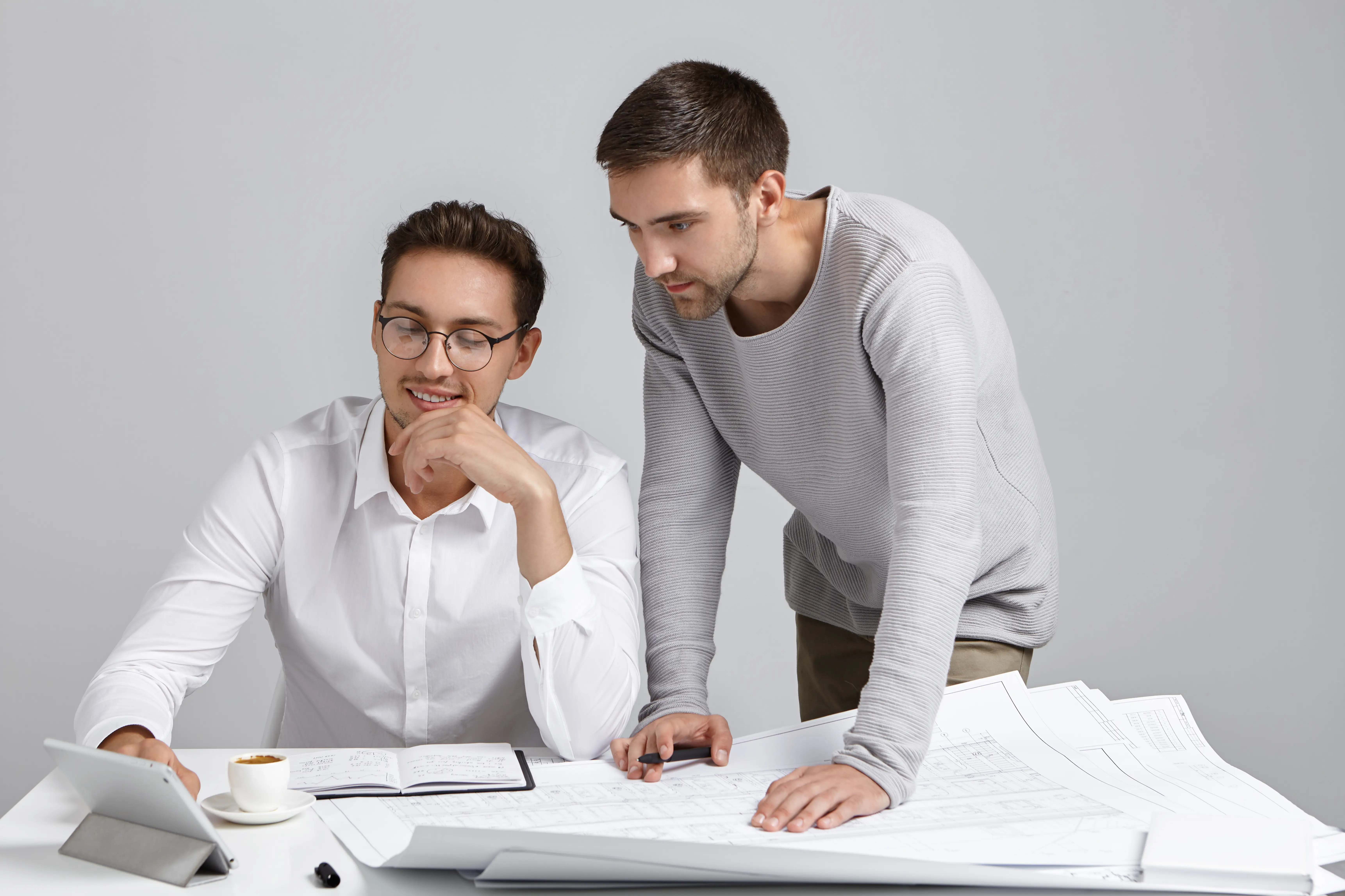 fashionable-young-male-architects-working-new-housing-project-together-checking-drawings-using-digital-tablet.webp